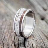 Shown here is "Raptor", a custom, handcrafted men's wedding ring featuring ironwood and antler inlays on a titanium band, upright facing left. Additional inlay options are available upon request.