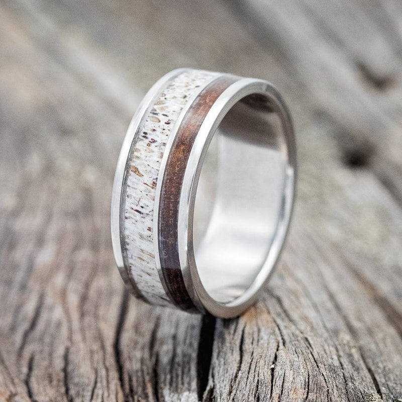 Shown here is "Raptor", a custom, handcrafted men's wedding ring featuring ironwood and antler inlays on a titanium band, upright facing left. Additional inlay options are available upon request.