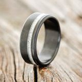 Shown here is "Vertigo", a custom, handcrafted men's wedding ring featuring an antler inlay with a sandblasted finish on a fire-treated black zirconium band, upright facing left. Additional inlay options are available upon request.