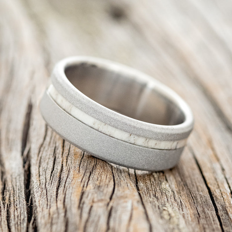 Shown here is "Vertigo", a custom, handcrafted men's wedding ring featuring an antler inlay with a sandblasted finish, tilted left. Additional inlay options are available upon request.