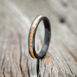 Shown here is "Eterna", a custom, handcrafted women's stacking band featuring a spalted maple inlay, shown here on a black zirconium band, upright facing left. Additional inlay options are available upon request.