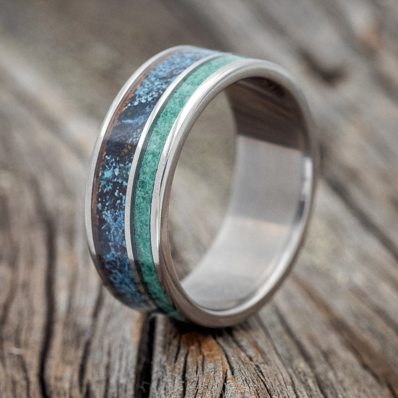 Shown here is "Raptor", a custom, handcrafted men's wedding ring featuring patina copper and malachite inlays, upright facing left. Additional inlay options are available upon request.