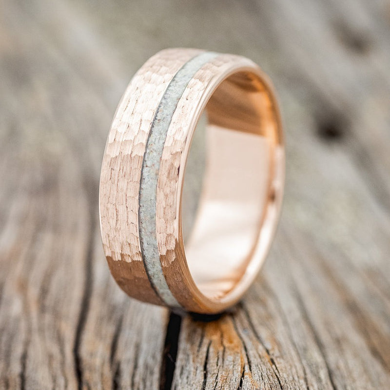 Shown here is "Vertigo", a custom, handcrafted men's wedding ring featuring a 14K gold wedding band with an opal inlay and hammered finish, upright facing left. Additional inlay options are available upon request.