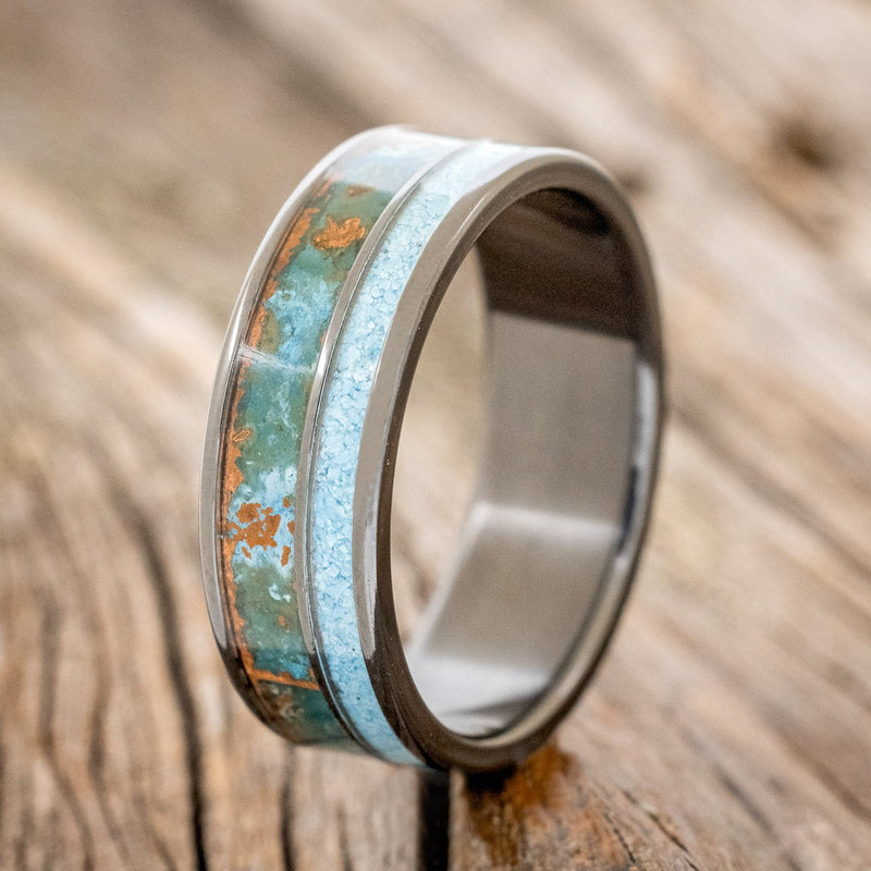 Shown here is "Raptor", a custom, handcrafted men's wedding ring featuring a patina copper and turquoise inlay on a fire-treated black zirconium band, upright facing left. Additional inlay options are available upon request.