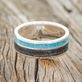 Shown here is "Raptor", a custom, handcrafted men's wedding ring featuring a patina copper and turquoise inlay, laying flat. Additional inlay options are available upon request.