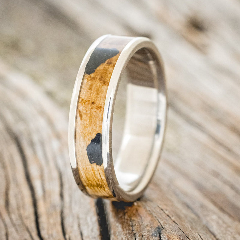 Shown here is "Rainier", a custom, handcrafted men's wedding ring featuring a whiskey barrel oak and charred whiskey barrel inlay on a titanium band, upright facing left. Additional inlay options are available upon request.