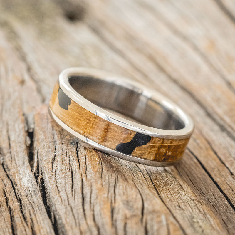 Shown here is "Rainier", a custom, handcrafted men's wedding ring featuring a whiskey barrel oak and charred whiskey barrel inlay on a titanium band, tilted left. Additional inlay options are available upon request.