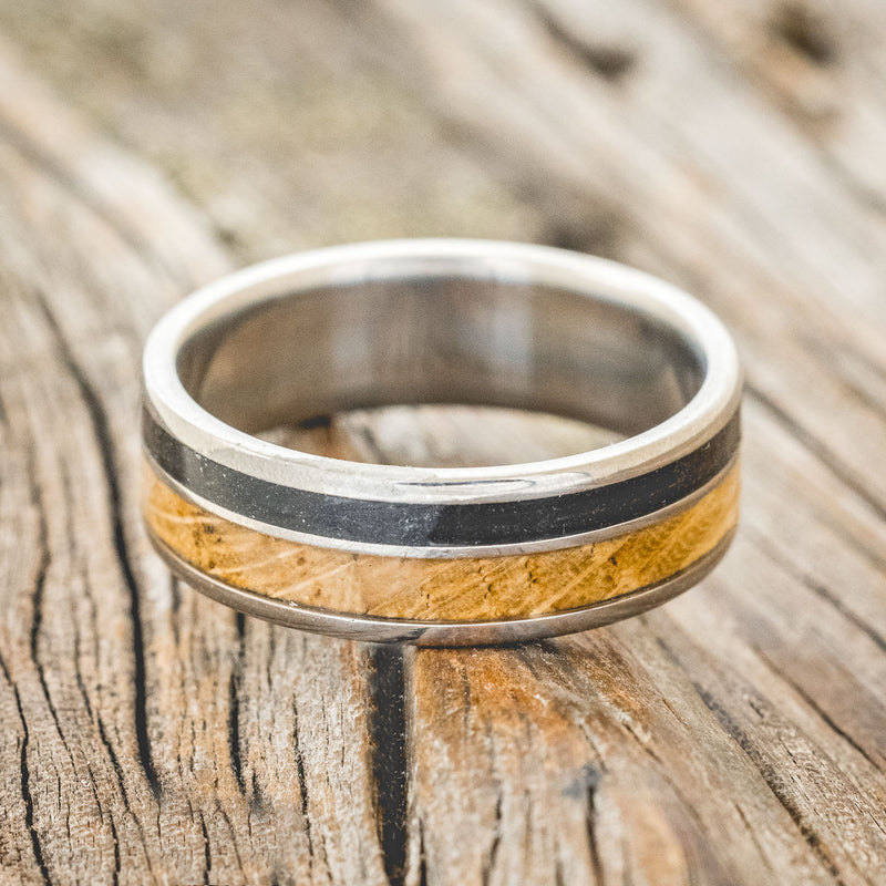 Shown here is "Raptor", a custom, handcrafted men's wedding ring featuring authentic whiskey barrel oak and charred whiskey barrel inlays, laying flat. Additional inlay options are available upon request.