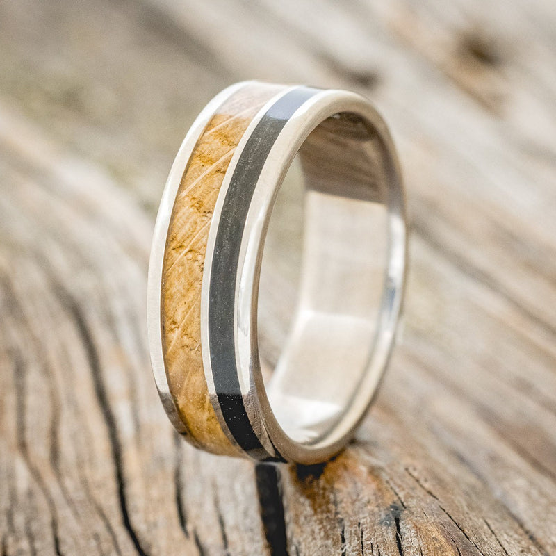Shown here is "Raptor", a custom, handcrafted men's wedding ring featuring authentic whiskey barrel oak and charred whiskey barrel inlays, upright facing left. Additional inlay options are available upon request.