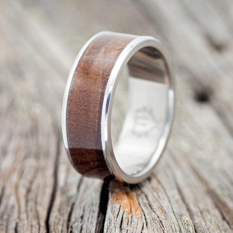 Shown here is "Rainier", a custom, handcrafted men's wedding ring featuring a koa wood inlay, upright facing left. Additional inlay options are available upon request.