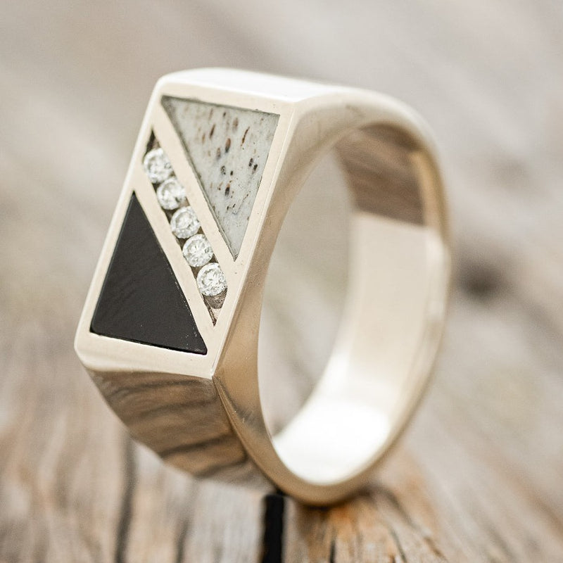 Shown here is "Alden", a custom, handcrafted men's wedding ring featuring black onyx, antler, and 1/3 CTW diamond accents, upright facing left. Additional inlay options are available upon request.