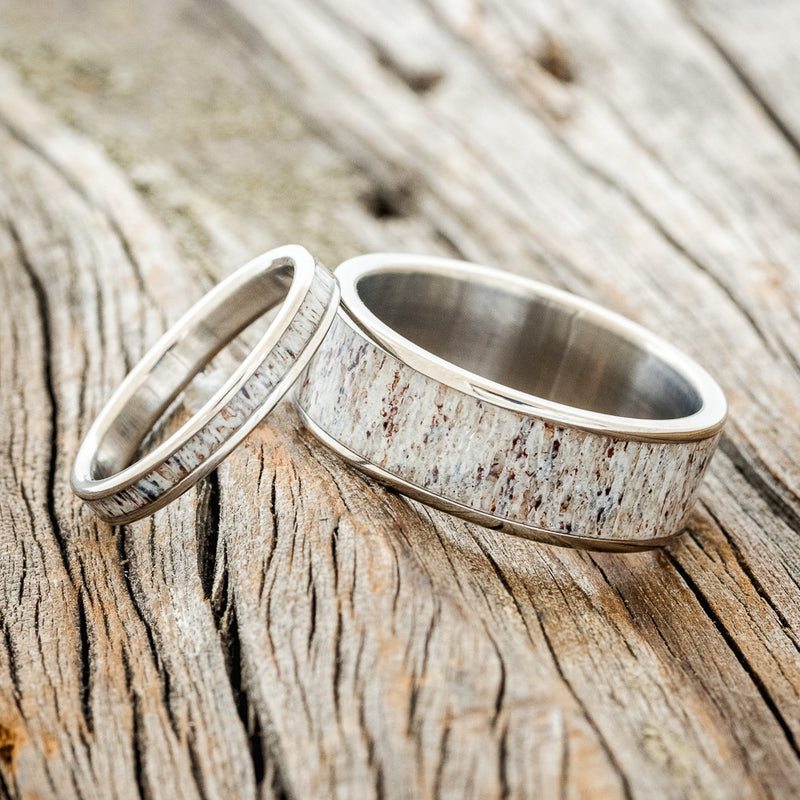 Shown here is a matching wedding band set featuring "Eterna" & "Rainier", laying together. "Rainier" is a handcrafted wide wedding band featuring an antler inlay. "Eterna" is a stacking-style wedding band featuring an antler inlay.