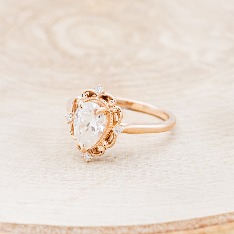 Shown here is "Vera", a vintage-style moissanite women's engagement ring with diamond accents, facing left. Many other center stone options are available upon request.