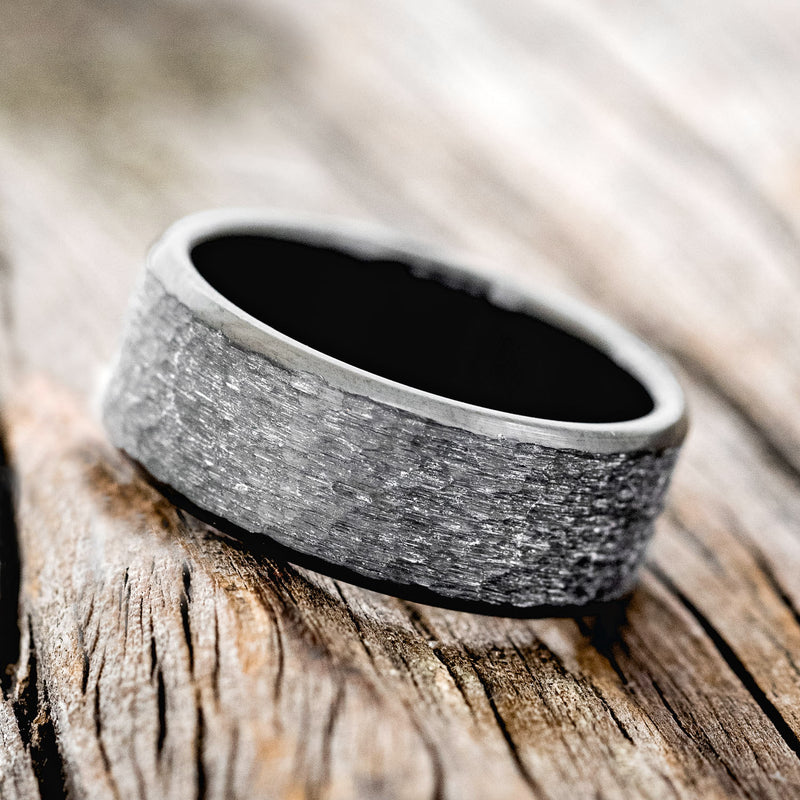 Shown here is a handcrafted men's wedding ring featuring a fire-treated black zirconium band with a hammered finish, tilted left. Additional inlay options are available upon request.