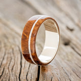 Shown here is "Remmy", a custom, handcrafted men's wedding ring featuring a redwood overlay and an offset mother of pearl inlay, upright facing left. Additional inlay options are available upon request.