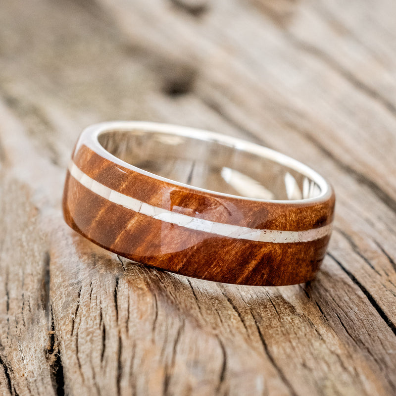 Shown here is "Remmy", a custom, handcrafted men's wedding ring featuring a redwood overlay and an offset mother of pearl inlay, tilted left. Additional inlay options are available upon request.