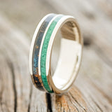 Shown here is "Dyad", a custom, handcrafted men's wedding ring featuring 2 channels with malachite and patina copper inlays on a 14K gold band, upright facing left. Additional inlay options are available upon request.