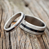 Shown here is "Nirvana", a matching wedding band set featuring individual patina copper inlays, shown here on hammered titanium bands, upright facing left.