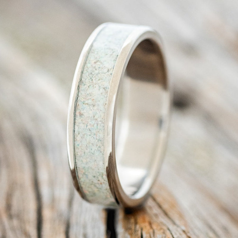 Shown here is "Rainier", a custom, handcrafted men's wedding ring featuring a fire and ice opal inlay, upright facing left. Additional inlay options are available upon request.