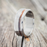 Shown here is "Vertigo", a handcrafted men's wedding ring featuring an offset ironwood inlay, upright facing left.