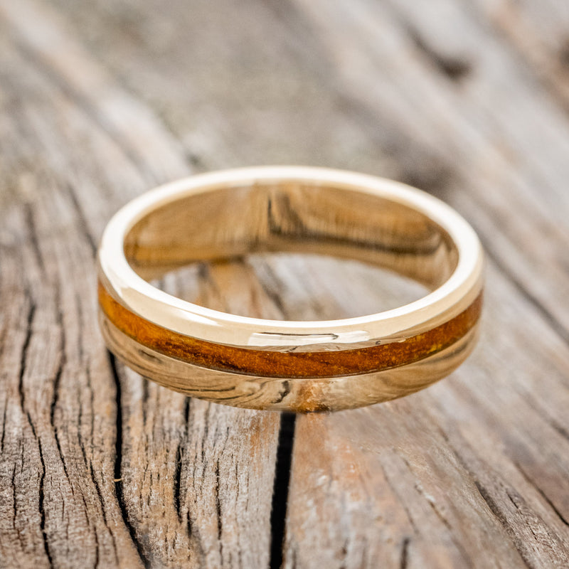 Shown here is "Vertigo" a handcrafted men's wedding ring featuring an offset ironwood inlay, laying flat. 