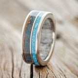 Shown here is "Raptor", a custom, handcrafted antler lined men's wedding ring featuring patina copper and hand-crushed turquoise inlays, upright facing left. Additional inlay options are available upon request.