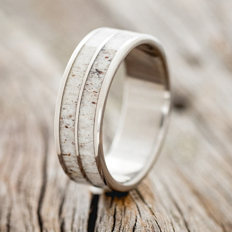 Shown here is "Dyad", a custom, handcrafted men's wedding ring featuring 2 channels with antler inlays, upright facing left. Additional inlay options are available upon request.