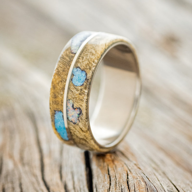 Shown here is "Golden", a custom, handcrafted men's wedding ring featuring a buckeye burl overlay with turquoise and fire & ice opal inlays filling the burls, upright facing left.