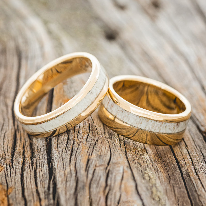 Shown here is a matching wedding band set featuring two "Castor" rings with antler inlays on 14K gold bands, laying together.