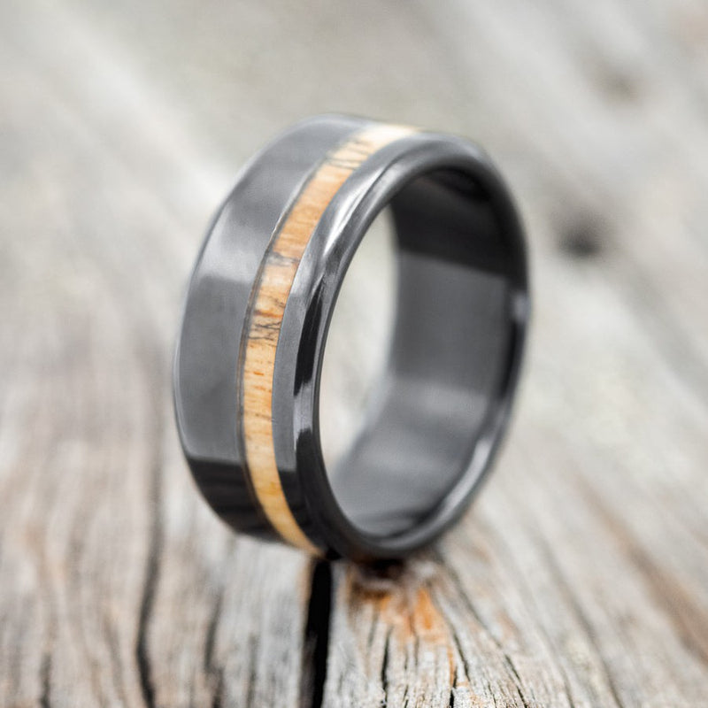 Shown here is "Vertigo", a custom, handcrafted men's wedding ring featuring a spalted maple inlay, upright facing left. Additional inlay options are available upon request.