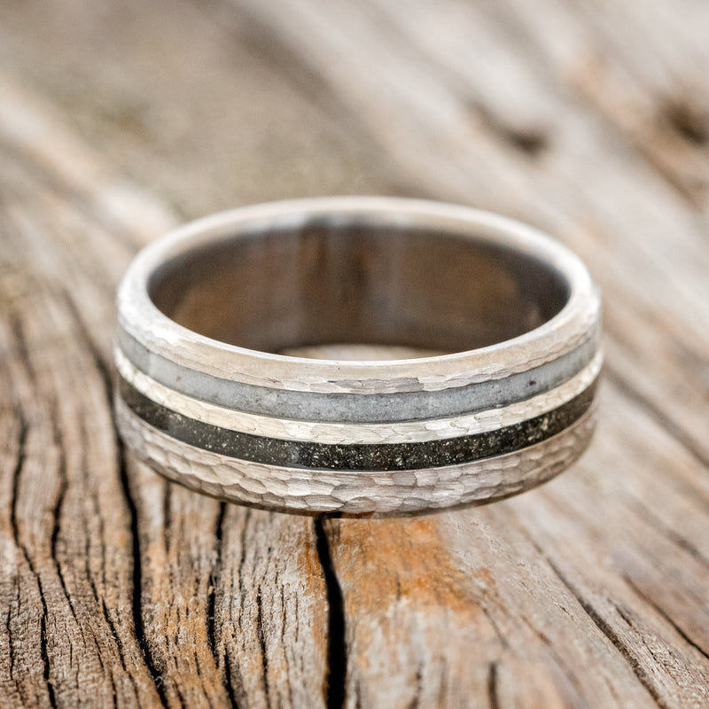 Shown here is "Cosmo", a custom, handcrafted men's wedding ring featuring a hammered band with iron ore, hammered silver, and elk antler inlays, laying flat. Additional inlay options are available upon request.