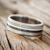 Shown here is "Cosmo", a custom, handcrafted men's wedding ring featuring a hammered band with iron ore, hammered silver, and elk antler inlays, tilted left. Additional inlay options are available upon request.