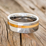 Shown here is "Vertigo", a custom, handcrafted men's wedding ring featuring a Bethlehem olive wood inlay, laying flat. Additional inlay options are available upon request.