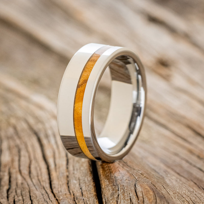 Shown here is "Vertigo", a custom, handcrafted men's wedding ring featuring a Bethlehem olive wood inlay, upright facing left. Additional inlay options are available upon request.