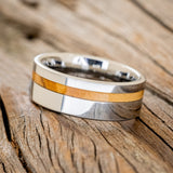 Shown here is "Vertigo", a custom, handcrafted men's wedding ring featuring a Bethlehem olive wood inlay, tilted left. Additional inlay options are available upon request.