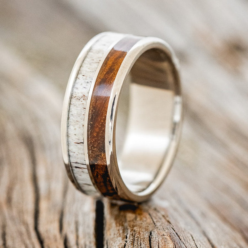 Shown here is "Dyad", a custom, handcrafted men's wedding ring featuring 2 channels with desert ironwood and elk antler inlays, upright facing left. Additional inlay options are available upon request.
