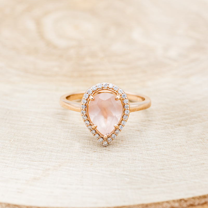 Shown here is "Clariss", a rose quartz women's engagement ring with a diamond halo, front facing. Many other center stone options are available upon request.