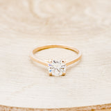 Shown here is a solitaire-style moissanite women's engagement ring with 4 claw prongs, front facing. Many other center stone options are available upon request.