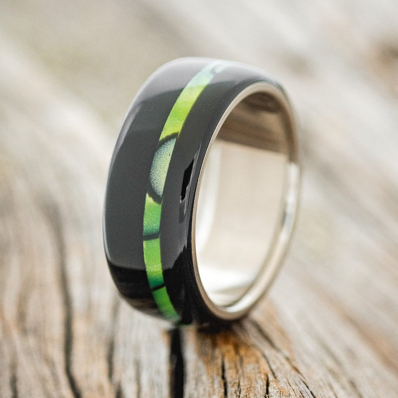 Shown here is "Remmy", a custom, handcrafted men's wedding ring featuring a hand-turned black and nuclear lime acrylic on a titanium band, upright facing left. Additional inlay options are available upon request.