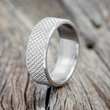 Shown here is a handcrafted men's wedding ring featuring a hand-turned solid metal wedding band with a knurled finish, upright facing left. We offer this style in our regular 8mm wide band as well as a wide 10mm wide band.