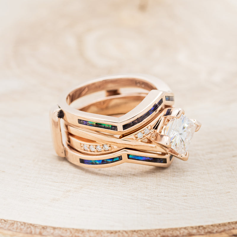 Shown here is "Lina", a moissanite women's engagement ring with diamond accents and a paua shell ring guard, facing right. Many other center stone options are available upon request.
