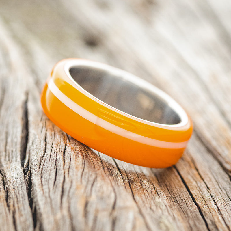 Shown here is "Remmy", a custom, handcrafted men's wedding ring featuring a hand-turned orange & white acrylic, tilted left. Additional inlay options are available upon request.