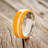 Shown here is "Remmy", a custom, handcrafted men's wedding ring featuring a hand-turned orange & white acrylic, upright facing left. Additional inlay options are available upon request.