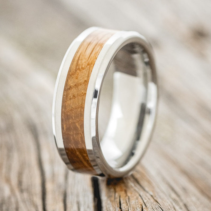 Shown here is a custom, handcrafted men's wedding ring featuring a whiskey barrel inlay with a tungsten band, upright facing left. Additional inlay options are available upon request.