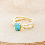 Shown here is "Anastasia", a split shank-style turquoise women's engagement ring with diamond accents, facing left.