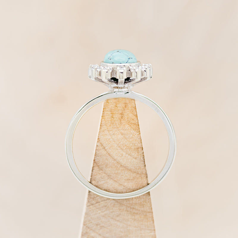 Shown here is "Shania", a turquoise women's engagement ring with diamond accents, side view on stand. Many other center stone options are available upon request.
