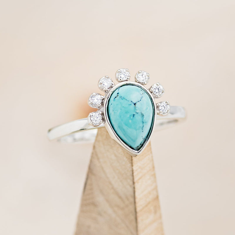 Shown here is "Shania", a turquoise women's engagement ring with diamond accents, on stand front facing. Many other center stone options are available upon request. 