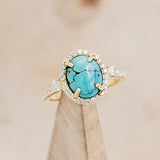 Shown here is "KB", a halo-style oval turquoise women's engagement ring with diamond accents, on stand front facing. Many other center stone options are available upon request.