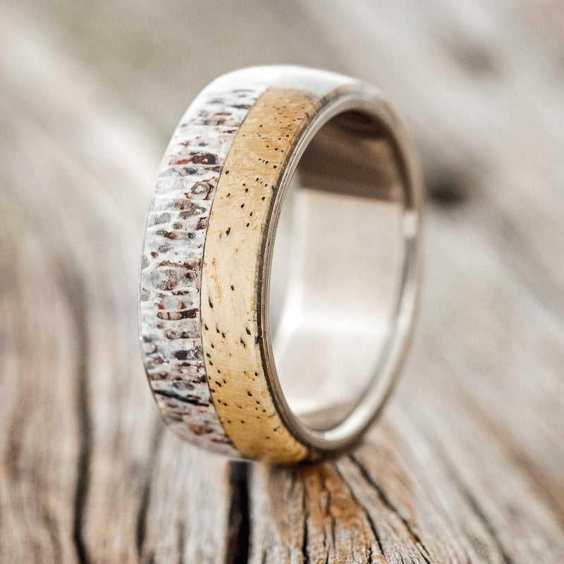 Shown here is "Arlo", a handcrafted men's wedding ring featuring spalted maple and antler overlay on a titanium band, upright facing left. Additional overlay options are available upon request.