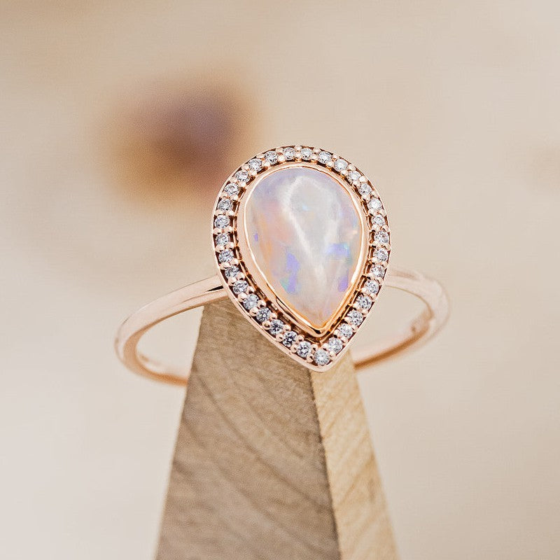 Shown here is "Terra", a halo-style Opal women's engagement ring, on stand facing slightly right, with delicate and ornate details and is available with many center stone options